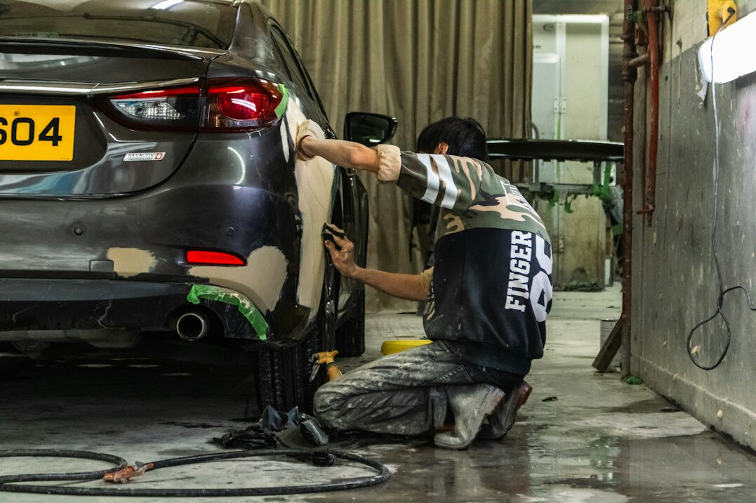 Mechanic inspecting the bodywork of a car in a garage