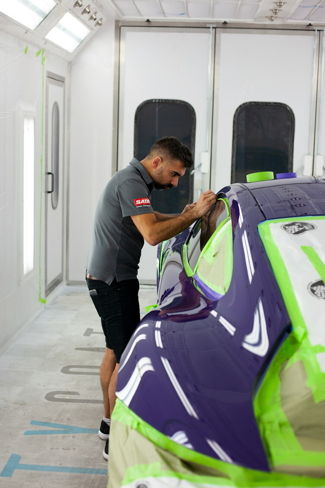 Technician sanding a car door panel before painting